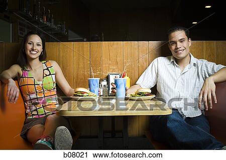 Stock Image - Couple on a date eating hamburgers. Fotosearch