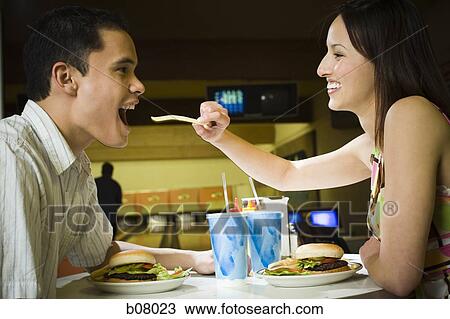 Stock Image - Couple on a date eating hamburgers. Fotosearch