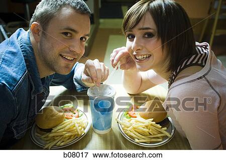 Couple on a date eating hamburgers View Large Photo Image Stock Photo - Couple on a date eating hamburgers. Fotosearch