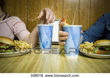 Couple on a date eating hamburgers View Large Photo Image Stock Photo - Couple on a date eating hamburgers. Fotosearch