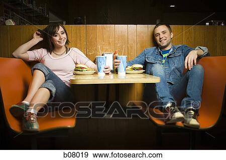 Couple on a date eating hamburgers View Large Photo Image Stock Photo - Couple on a date eating hamburgers. Fotosearch