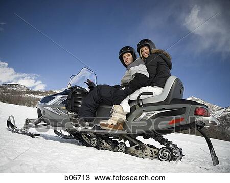 Stock Image - Couple on snow mobile. Fotosearch