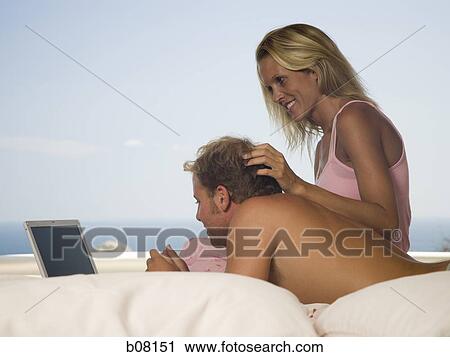 Couple relaxing on terrace looking at laptop View Large Photo Image Stock Image - Couple relaxing on terrace looking at laptop. Fotosearch