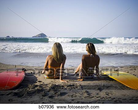Stock Photograph - Couple sitting on a beach. Fotosearch