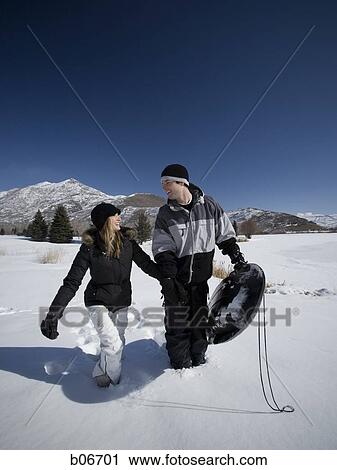Couple walking with toboggan View Large Photo Image Stock Image - Couple walking with toboggan. Fotosearch