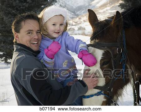 Picture - Father and daughter petting horse. Fotosearch