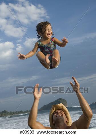 Stock Image - Father playing with young daughter on beach. Fotosearch
