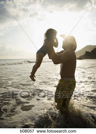 Stock Photo - Father playing with young daughter on beach. Fotosearch