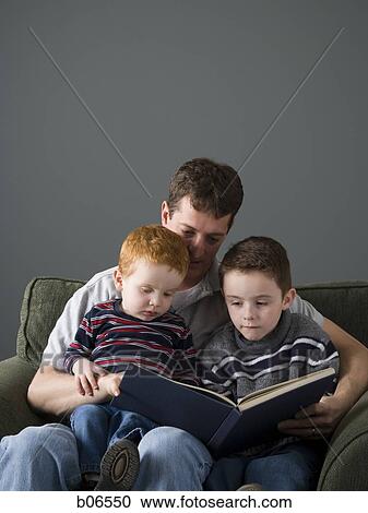 Stock Image - Father reading book with sons. Fotosearch