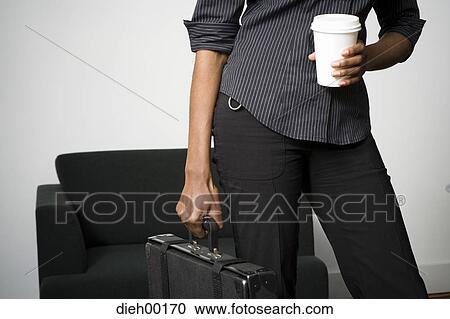 Stock Image - Female African-American woman standing and holding briefcase. Fotosearch