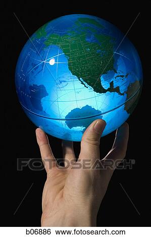 Stock Photograph - Hand holding earth globe on fingertips. Fotosearch