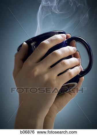 Stock Photograph - Hand holding hot cup of coffee. Fotosearch