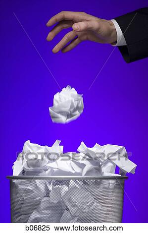 Stock Photography - Hand tossing paper into trash can. Fotosearch