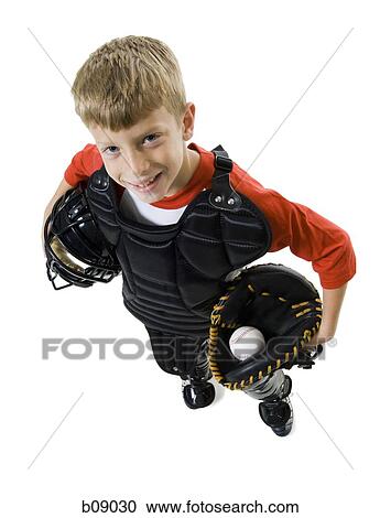 Stock Image - High angle view of a baseball catcher holding a baseball helmet and a catchers mit. Fotosearch