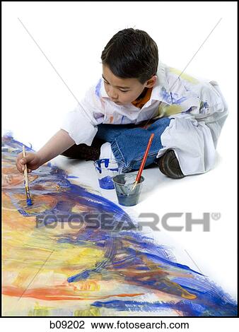 Stock Image - High angle view of a boy painting on the floor. Fotosearch