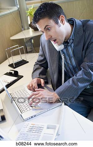 High angle view of a businessman using a laptop and talking on the telephone View Large Photo Image Picture - High angle view of a businessman using a laptop and talking on the telephone. Fotosearch