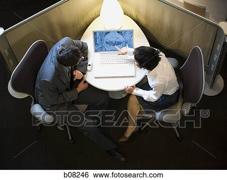 Stock Photograph - High angle view of a businesswoman and a businessman looking at a laptop. Fotosearch
