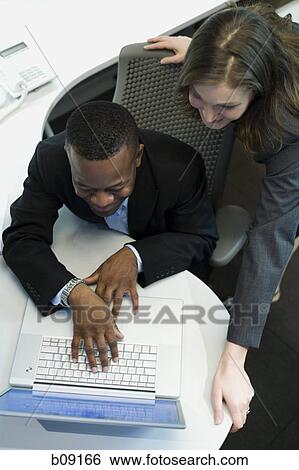 Stock Photograph - High angle view of a businesswoman and a businessman using a laptop. Fotosearch