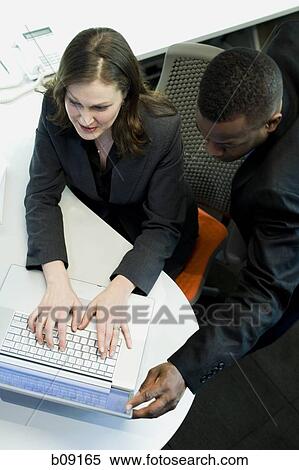Stock Photography - High angle view of a businesswoman and a businessman using a laptop. Fotosearch