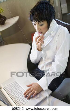 High angle view of a businesswoman using a laptop and talking on the telephone View Large Photo Image Stock Image - High angle view of a businesswoman using a laptop and talking on the telephone. Fotosearch