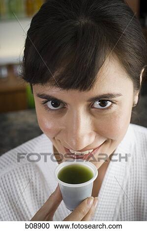 High angle view of a young woman holding a glass of wheatgrass juice View Large Photo Image Stock Image - High angle view of a young woman holding a glass of wheatgrass juice. Fotosearch