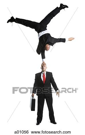 Stock Photograph - High angle view of two male acrobats in business suits performing. Fotosearch