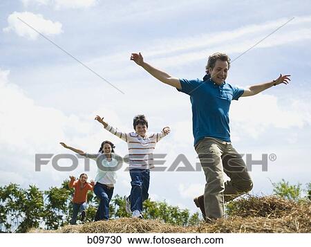 Low angle view of a man and a woman jumping with their children on hay bales View Large Photo Image Stock Image - Low angle view of a man and a woman jumping with their children on hay bales. Fotosearch