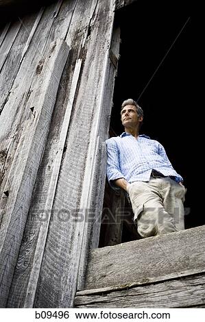 Low angle view of a man leaning against a wooden wall View Large Photo Image Stock Photograph - Low angle view of a man leaning against a wooden wall. Fotosearch
