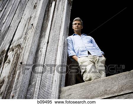 Low angle view of a man leaning against a wooden wall View Large Photo Image Stock Photography - Low angle view of a man leaning against a wooden wall. Fotosearch