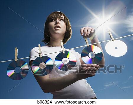 Picture - Low angle view of a teenage girl drying CDs on a clothesline. Fotosearch