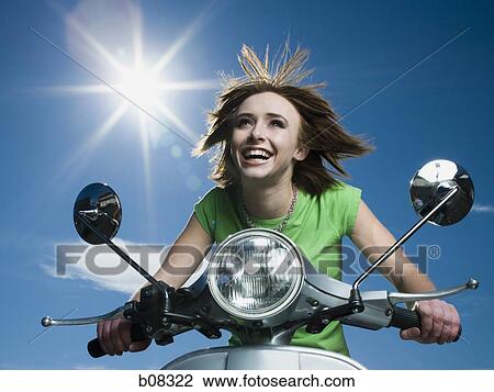 Low angle view of a teenage girl riding a scooter View Large Photo Image Stock Image - Low angle view of a teenage girl riding a scooter. Fotosearch