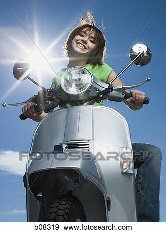 Stock Photo - Low angle view of a teenage girl riding a scooter. Fotosearch