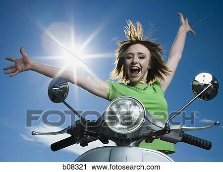 Low angle view of a teenage girl standing on a scooter with her arms raised View Large Photo Image Stock Image - Low angle view of a teenage girl standing on a scooter with her arms raised. Fotosearch