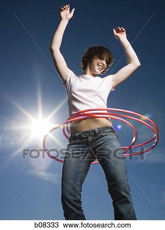 Stock Image - Low angle view of a teenage girl spinning hula hoops around her waist. Fotosearch