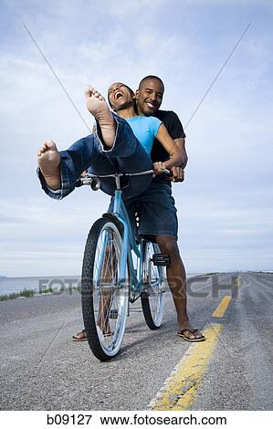 Low angle view of a young couple sitting on a bicycle View Large Photo Image Stock Photo - Low angle view of a young couple sitting on a bicycle. Fotosearch