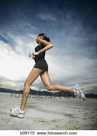 Low angle view of a young woman jogging View Large Photo Image Stock Image - Low angle view of a young woman jogging. Fotosearch