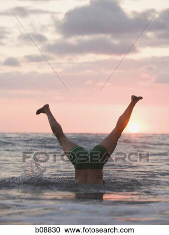 Low section view of a mature man doing a handstand in the sea View Large Photo Image Stock Image - Low section view of a mature man doing a handstand in the sea. Fotosearch