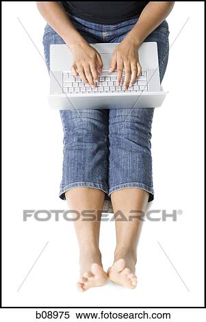 Low section view of a young woman sitting on the floor and using a laptop View Large Photo Image Stock Photography - Low section view of a young woman sitting on the floor and using a laptop. Fotosearch
