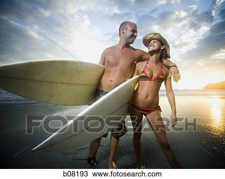 Male and female surfers holding surfboards View Large Photo Image Stock Image - Male and female surfers holding surfboards. Fotosearch
