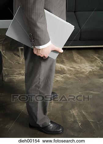 Male office worker waiting and holding a laptop View Large Photo Image Picture - Male office worker waiting and holding a laptop. Fotosearch
