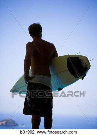 Male surfer holding surfboard View Large Photo Image Stock Image - Male surfer holding surfboard. Fotosearch