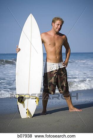 Male surfer holding surfboard View Large Photo Image Stock Photo - Male surfer holding surfboard. Fotosearch