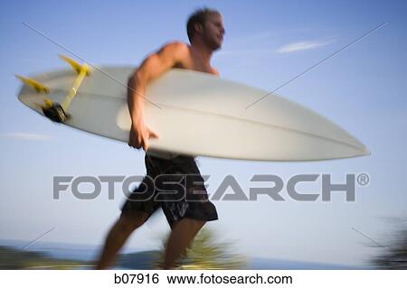 Male surfer holding surfboard View Large Photo Image Stock Photograph - Male surfer holding surfboard. Fotosearch