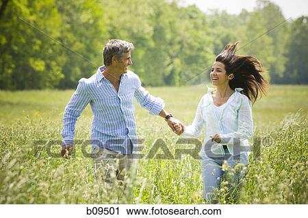 man and a woman holding hands and running in a field View Large Photo Image Stock Image - man and a woman holding hands and running in a field. Fotosearch