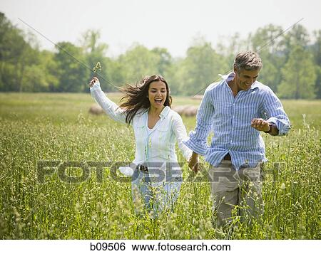 man and a woman holding hands in a field View Large Photo Image Stock Photograph - man and a woman holding hands in a field. Fotosearch