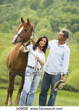 man and a woman standing with a horse View Large Photo Image Stock Image - man and a woman standing with a horse. Fotosearch