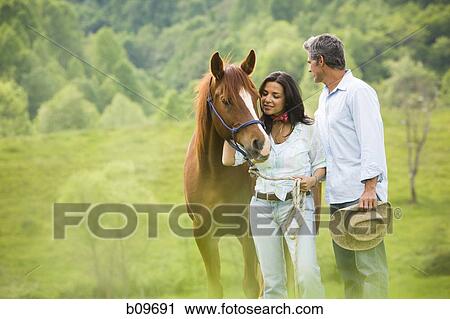 man and a woman standing with a horse View Large Photo Image Stock Image - man and a woman standing with a horse. Fotosearch