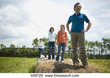 man and a woman standing with their children on hay bales View Large Photo Image Stock Photo - man and a woman standing with their children on hay bales. Fotosearch