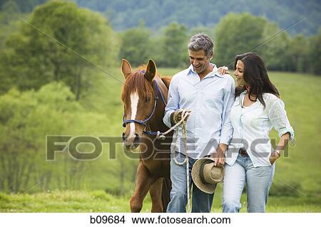 Picture - man and a woman walking with a horse. Fotosearch