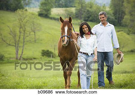 man and a woman walking with a horse View Large Photo Image Stock Photograph - man and a woman walking with a horse. Fotosearch